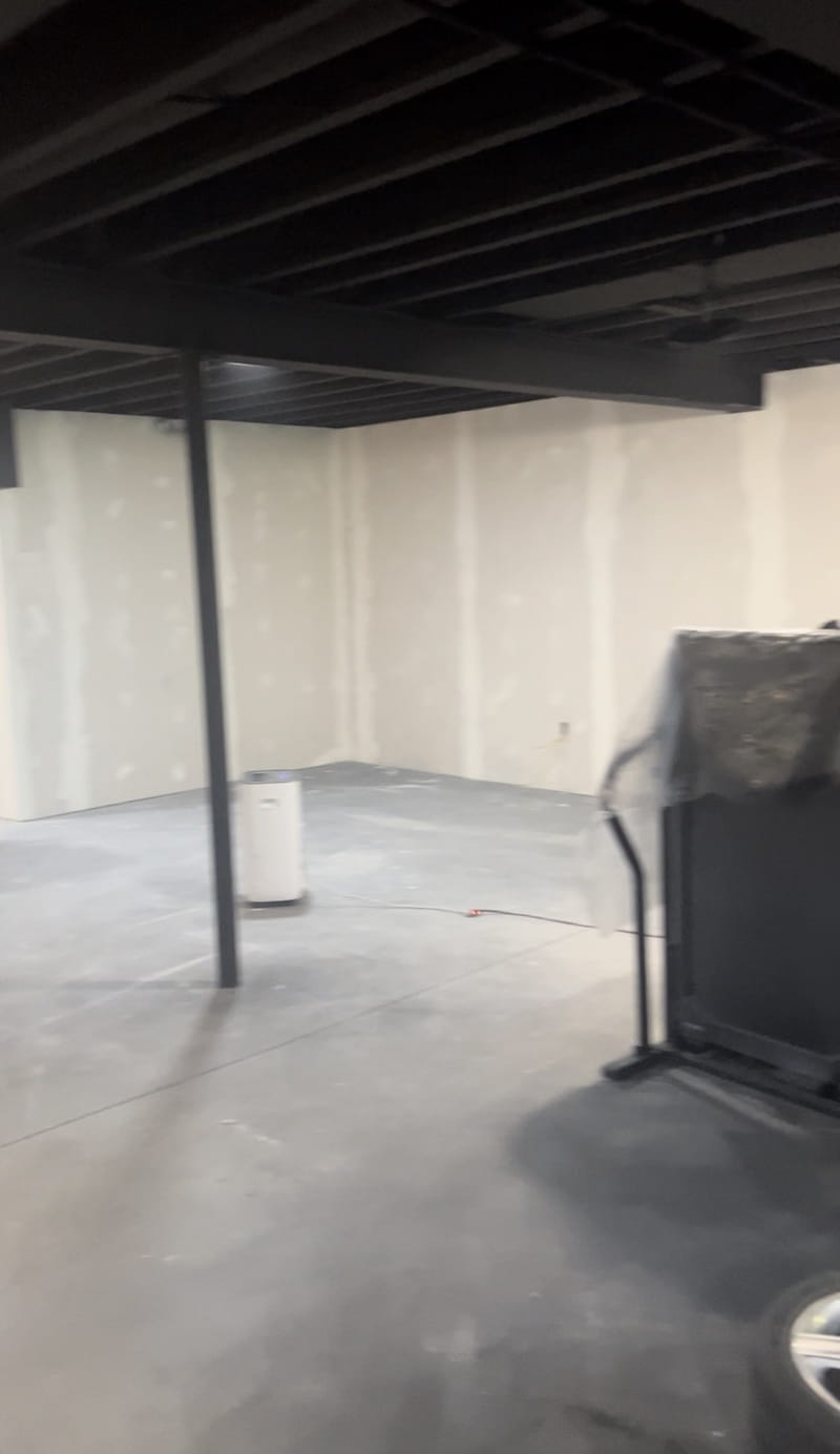 Finished basement with black painted ceiling, recessed lighting, white drywall walls, and clean floors