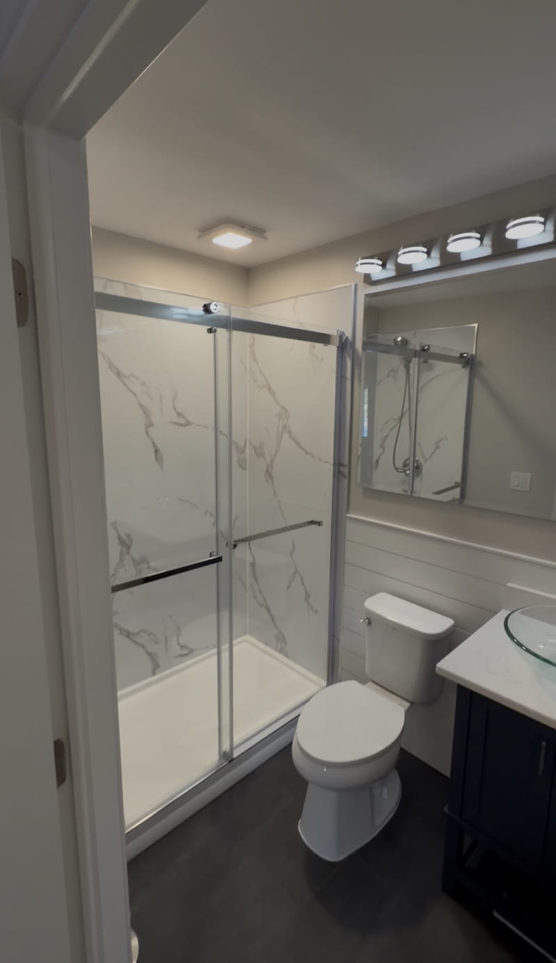 Bathroom from doorway showing frameless glass shower enclosure and vanity
