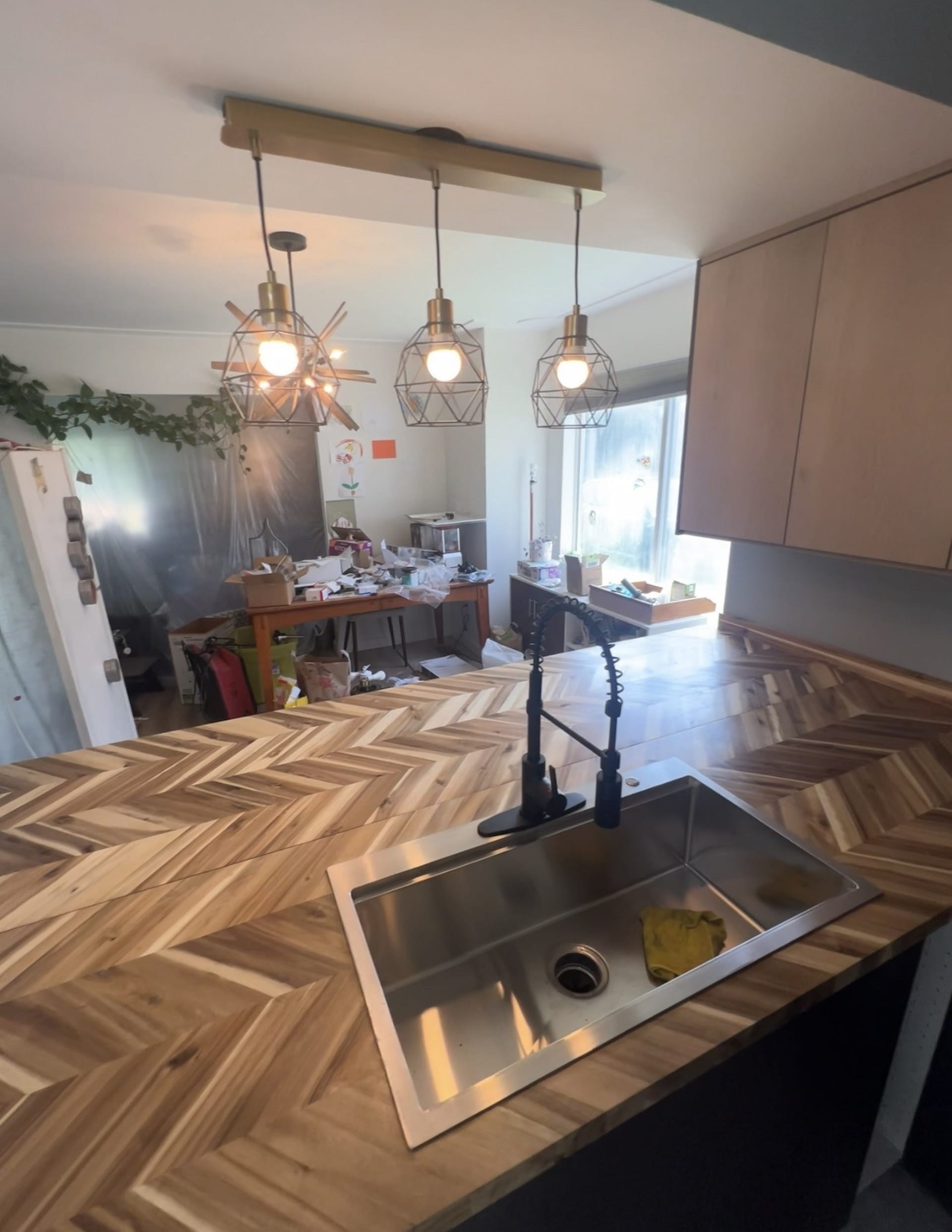 Finished kitchen with herringbone wood countertop island, pendant lights, and undermount sink in Rochester Hills home