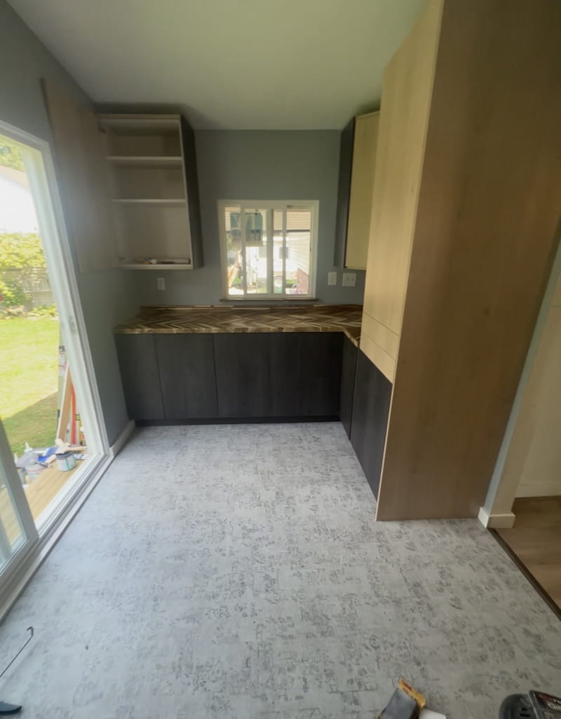 Full kitchen view showing dark lower cabinets, light upper cabinets, and new flooring