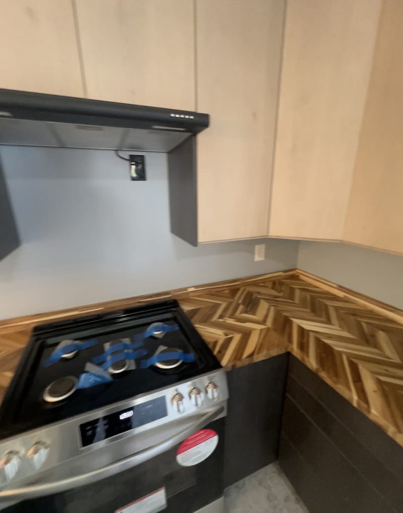 Kitchen stove area with range hood and herringbone countertop