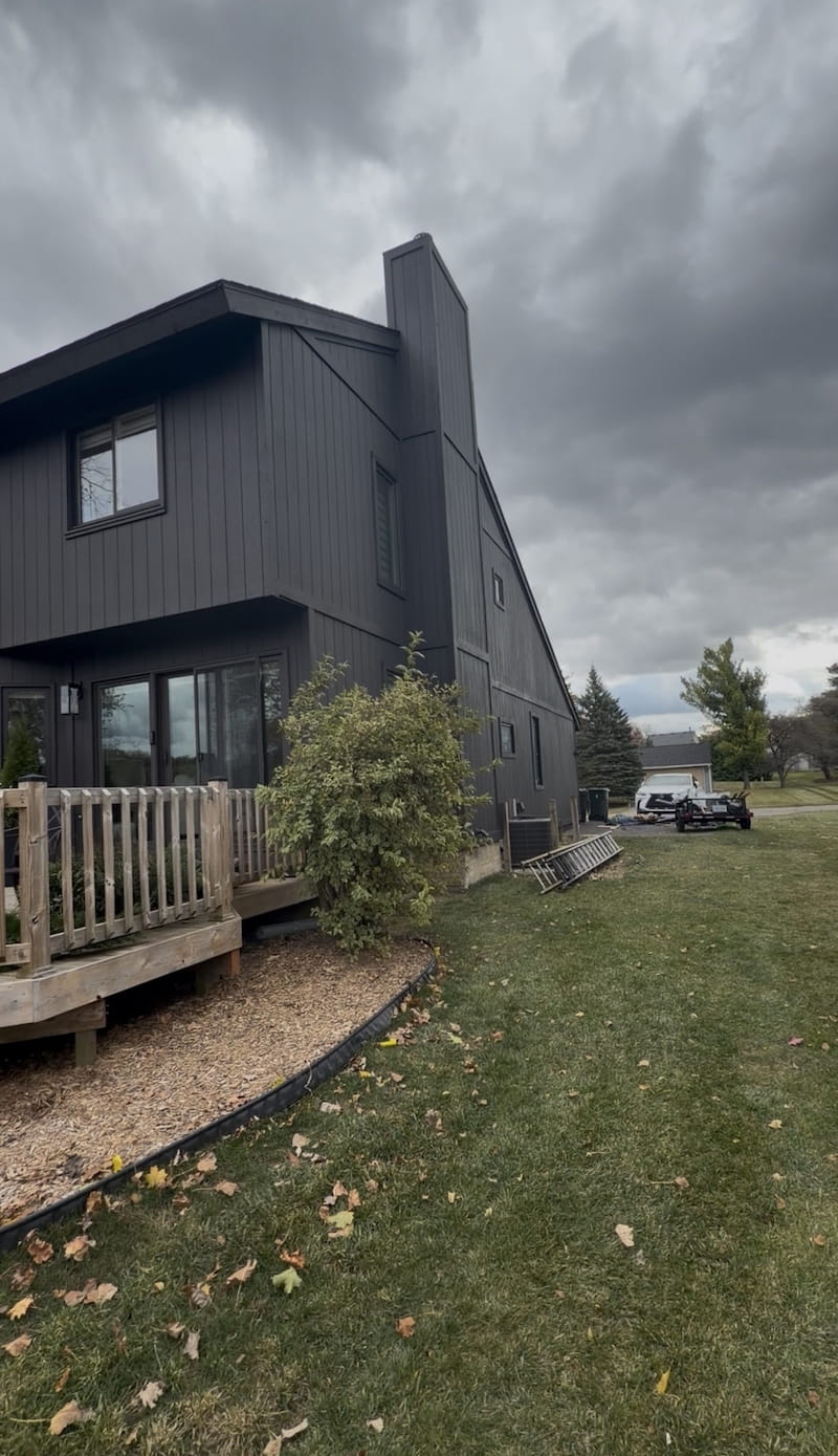 Side view of home with completed dark siding and wood deck